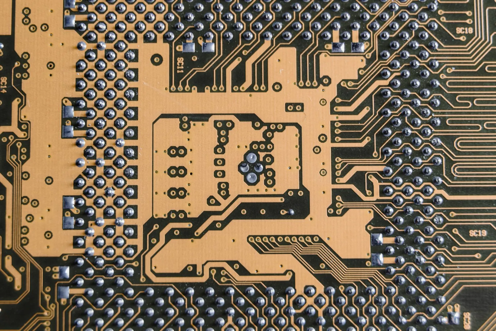 Bare circuit board close-up with solder-coated pads on a gold-plated copper pour
