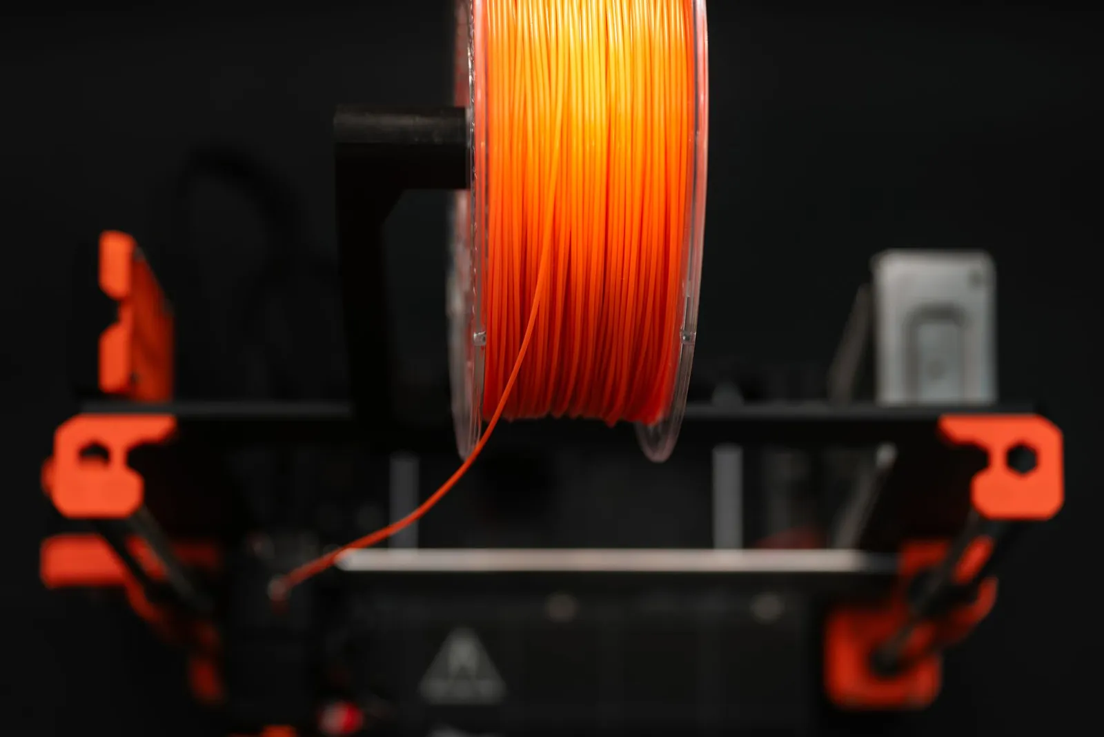 Orange filament spool mounted on a 3D printer